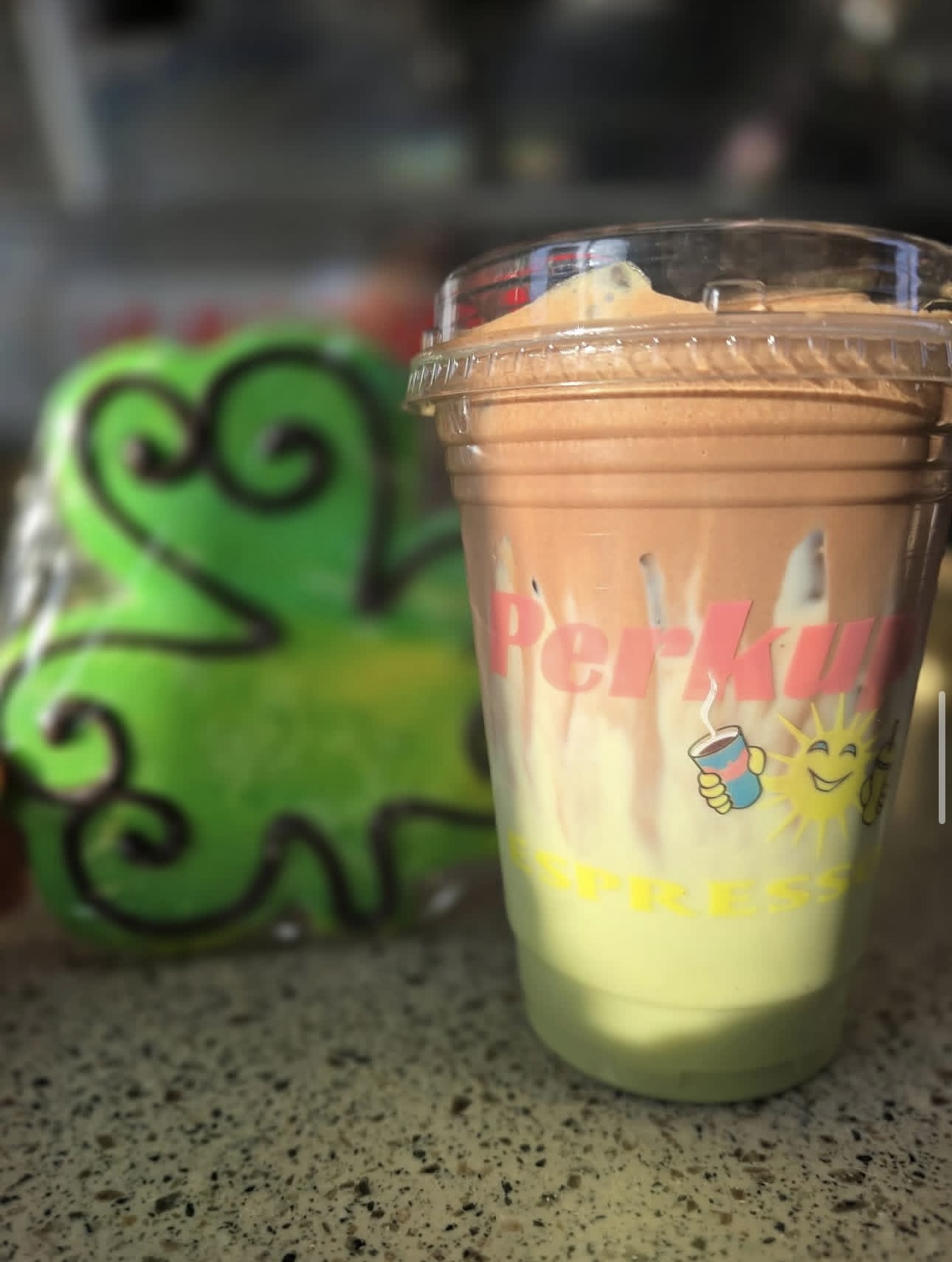 A blended Perkup Espresso drink beside a frosted cookie